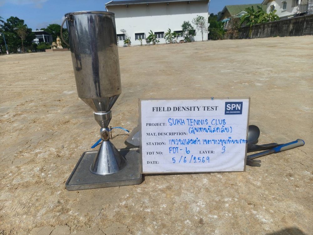 ชุดทดสอบ Field Density Test แบบ Sand Cone ตั้งบนพื้นที่ถมบดอัดของโครงการสนามเทนนิส พร้อมป้ายบันทึกจุดทดสอบ FDT และชั้นบดอัด โดย SPN