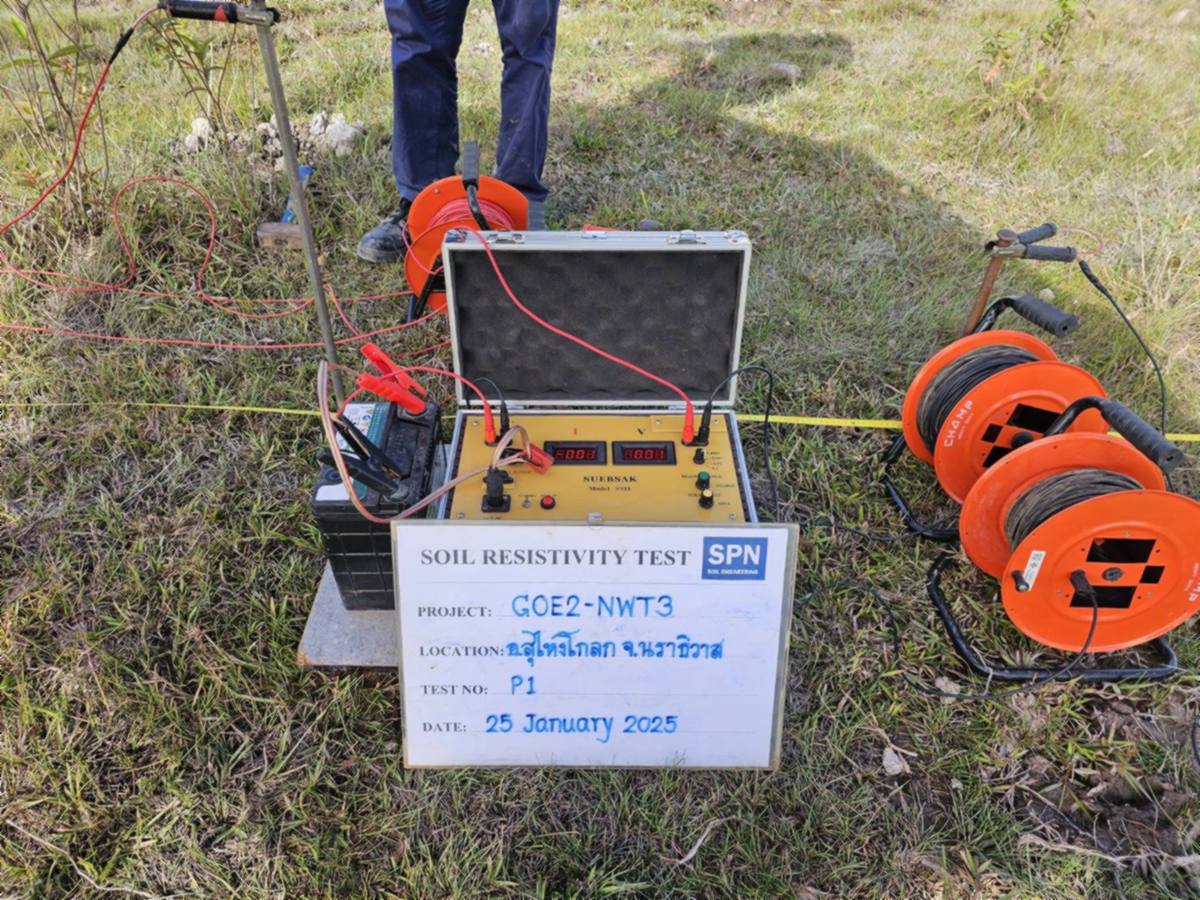 เครื่องวัดค่าความต้านทานไฟฟ้าของดิน Earth Resistivity Meter วางบนกล่อง พร้อมแบตเตอรี่จ่ายไฟและม้วนสายไฟสี่ม้วน ข้างกระดานบันทึกข้อมูลจุดทดสอบ