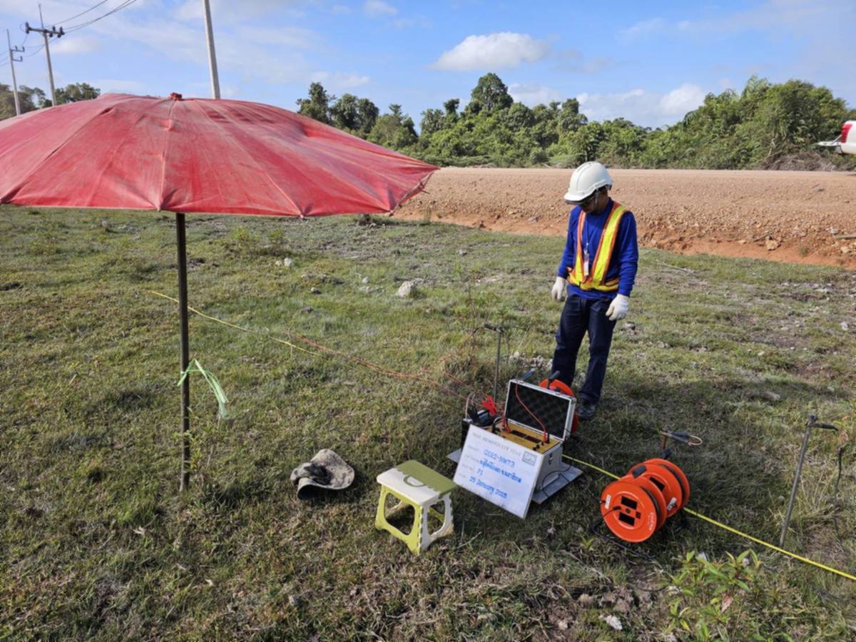 ทีมวิศวกร SPN ทดสอบ Soil Resistivity Test ในพื้นที่โครงการ ตั้งเครื่องวัดความต้านทานไฟฟ้าของดินบนพื้นหญ้า มีร่มบังแดดและม้วนสายไฟสีส้มวางข้างเครื่อง