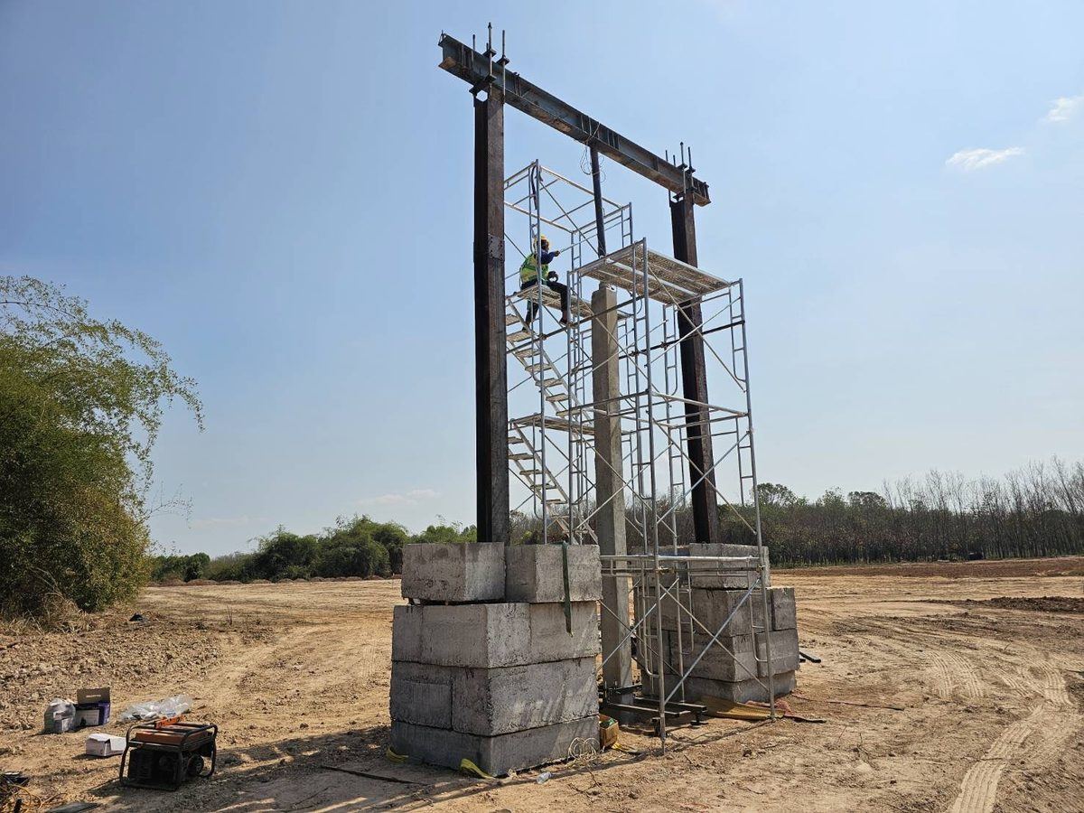 โครงเหล็กปฏิกิริยาสำหรับทดสอบเสาเข็มรับแรงกดแบบ Static Load Test ตั้งอยู่บนแท่นบล็อกคอนกรีตสองข้างในพื้นที่โครงการ